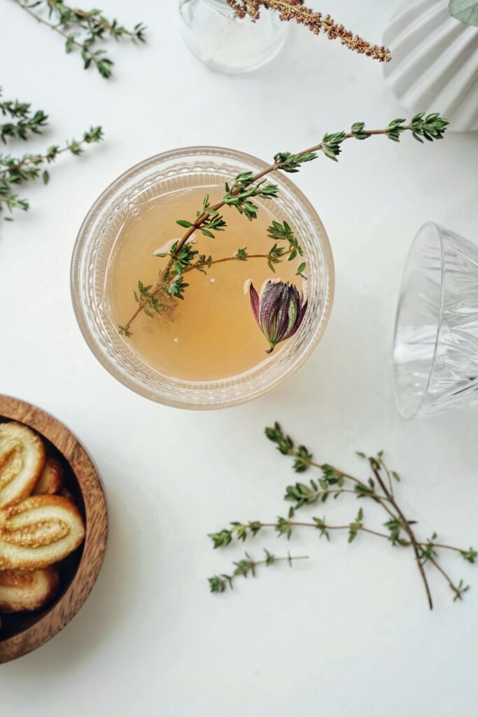 Elegant flatlay of herbal tea garnished with thyme and served with cookies, captured from above.