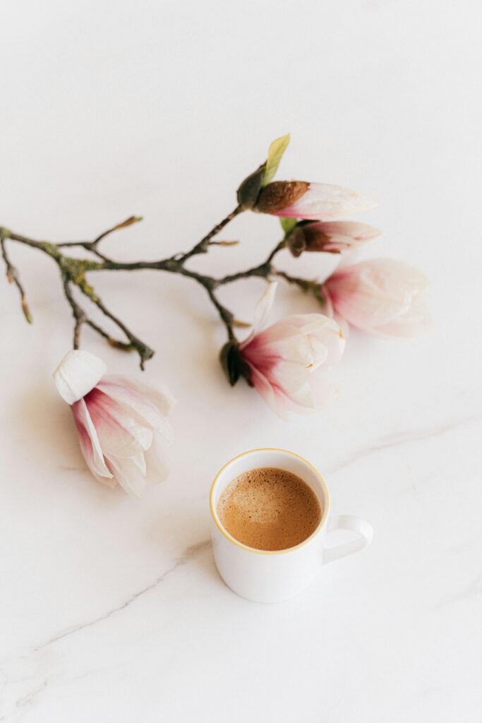 Delicate magnolia flowers with a fresh cup of coffee on a marble surface, evoking a peaceful morning vibe.